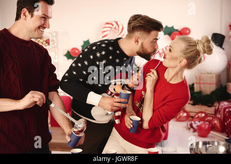 Jeune homme servant à perforer les amis at Christmas party Banque D'Images