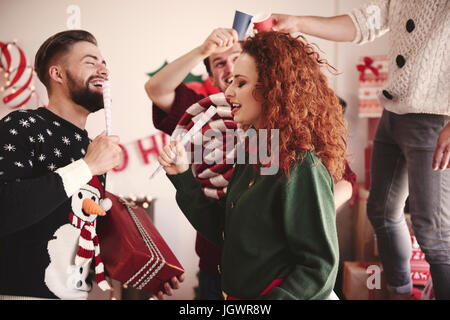 Jeune homme et femme chantant avec microphones prétendre at Christmas party Banque D'Images