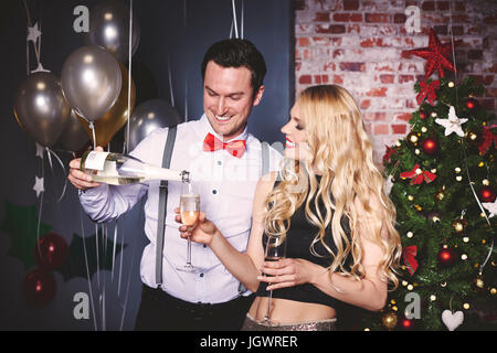 L'homme et de la femme au travail, l'homme pouring champagne en verre de la femme Banque D'Images