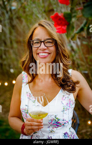 Portrait of woman at garden party, holding glass of wine, smiling Banque D'Images