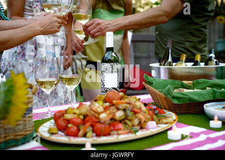 Groupe de personnes à la garden party, verres à vin, faire un toast, de l'alimentation sur le plat de service en premier plan, mid section Banque D'Images