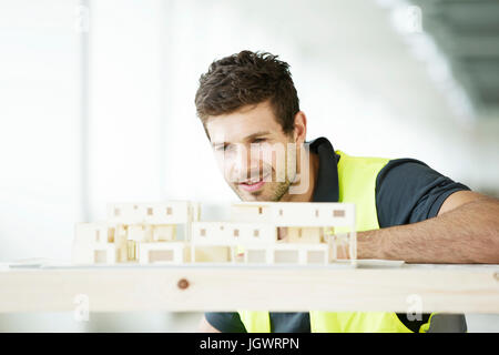 Homme portant un gilet haute visibilité, à la construction de modèle à Banque D'Images