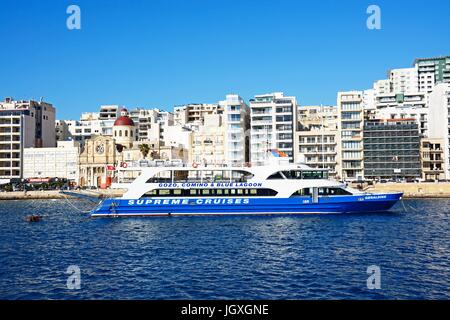 Avec vue sur la mer avec un bateau d'excursion à l'avant-plan et l'église paroissiale de Jésus de Nazareth à la gauche, Sliema, Malte, l'Europe. Banque D'Images