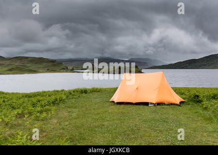 Camping sauvage sur la rive du Loch Assynt, avec le 16e siècle le château de Arvreck dans l'arrière-plan. Banque D'Images