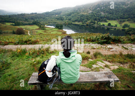 Une femme d'Asie de l'Est, s'asseoir sur un banc en regardant l'eau, Rydal Lake District, Cumbria, Royaume-Uni. Banque D'Images