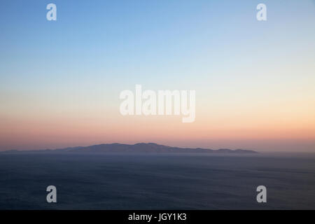 Seascape et vue lointaine de l'île d'Andros Île de Tinos, Grèce, au coucher du soleil Banque D'Images