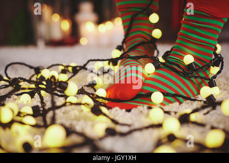 Pieds de femme portant des chaussettes à rayures enchevêtré dans fairy lights Banque D'Images