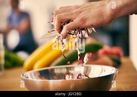 Placer les feuilles de salade Chef haché dans un bol Banque D'Images