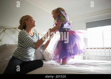 Jeune fille habillé en costume de fée, debout sur un lit, mother holding her hands Banque D'Images