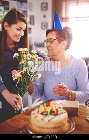 Fille mère donnant des fleurs at Birthday party Banque D'Images