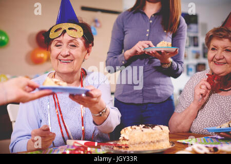 Les femmes âgées d'être servi le gâteau d'anniversaire at party Banque D'Images