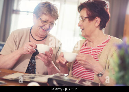 Deux femmes âgées de rire en regardant l'album photo sur tableau Banque D'Images