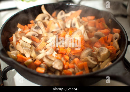 Poêlée de champignons délicieux champignons, la carotte et l'oignon dans le moule sur une cuisinière à gaz close-up Banque D'Images