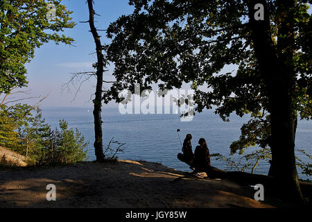 Les jeunes femmes faisant séance selfies sur le tronc de l'arbre sur la falaise à Gdynia Orlowo, dans le nord de la Pologne, 2015. Banque D'Images