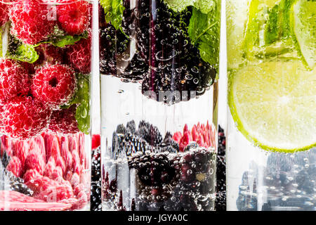 Trois types d'eau detox avec blackberry, fraise, citron vert avec des ingrédients sur fond de bois blanc. Banque D'Images