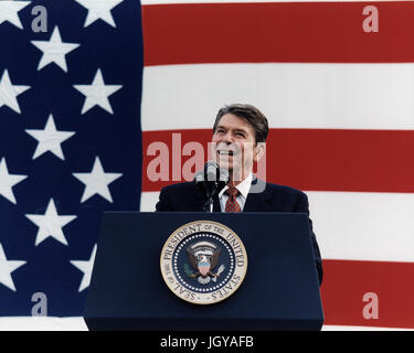 Le président Ronald Reagan prononce un discours devant un énorme drapeau Américain Banque D'Images