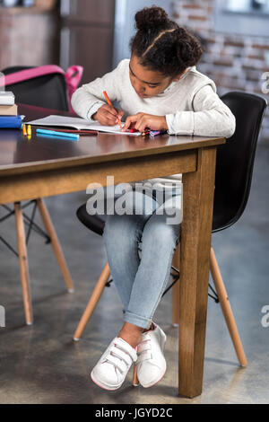 Sur toute la longueur de l'african american girl cute girl sitting at table et faire leurs devoirs Banque D'Images