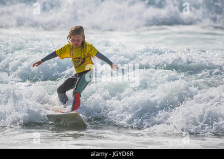 UK Surf. Enfant surf wave. Un surfeur de huit ans qui se font concurrence sur les écoles britanniques Championnat de Surf. Banque D'Images