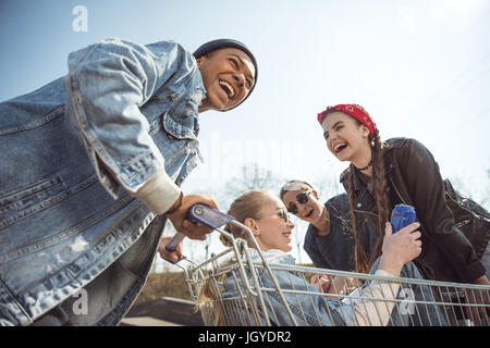 Groupe d'adolescents souriants s'amusant avec panier à skateboard park Banque D'Images