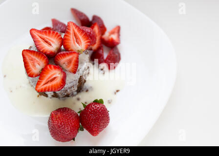 Délicieux gâteau au chocolat maison avec des fraises rouges frais et à la crème sur la plaque blanche. Banque D'Images