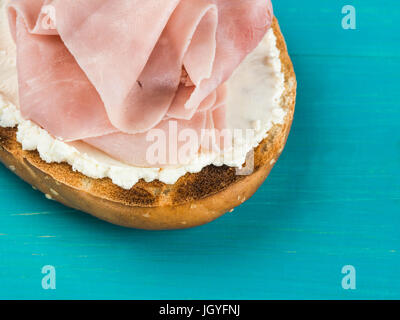 Jambon et fromage doux bagel sésame contre un fond bleu Banque D'Images