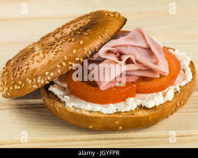 Jambon et fromage tomate bagel sésame contre un fond de bois en pin Banque D'Images