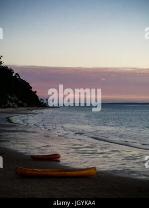 Deux canoës reposant sur une plage au coucher du soleil sur Fraser Island, Queensland, Australie. Banque D'Images