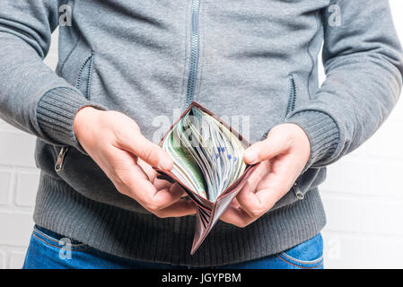 Un sac à main en cuir dans les mains des hommes est plein de dollars Banque D'Images