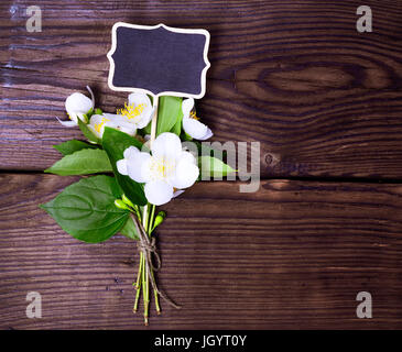 Bouquet de jasmin en fleurs avec des fleurs blanches et des feuilles vertes sur un fond en bois brun Banque D'Images