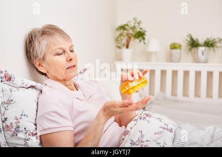 Sick senior woman in bed avec médicament à portée de main Banque D'Images