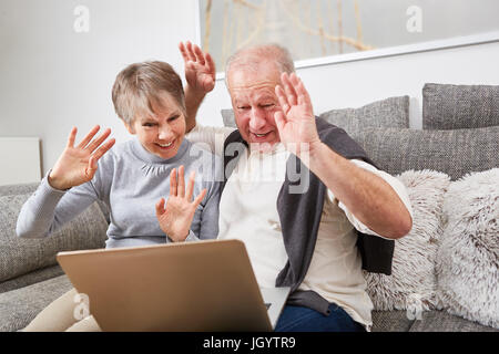 Senior couple vague à l'ordinateur tandis que le chat vidéo avec portable Banque D'Images