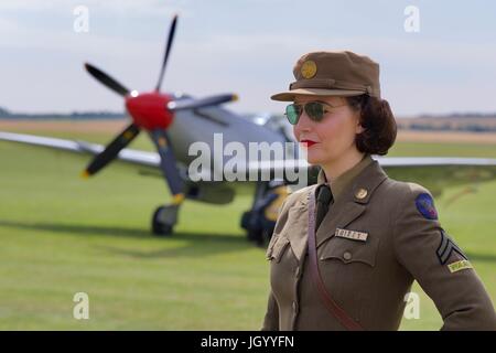 Une jeune femme habillée en uniforme avec une période de Supermarine Spitfire Mk XVIII G-BUOS dans l'arrière du terrain au Flying Legends Air Show 2017 Banque D'Images