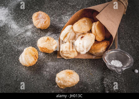 La cuisson à la maison, les feuilletés. La nourriture à la mode. Cronuts popcorn, puff, trous de beignes dans sac en papier avec du sucre en poudre. Sur une table en pierre. Copy space Banque D'Images