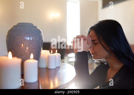 Femme triste avec urne funéraire en priant à l'église Banque D'Images