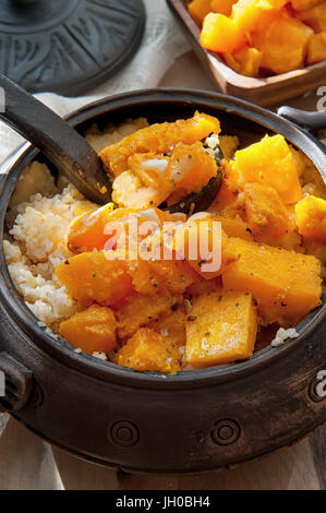 Bouillie de blé végétariens avec de grandes pièces d'orange citrouille frits juteux dans un pot en argile dans un style rustique Banque D'Images