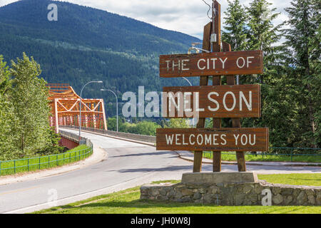 Panneau de bienvenue à l'entrée de la ville de Nelson, BC, Canada - à l'ouest du pont du Bras (Grand Pont Orange) dans l'arrière-plan Banque D'Images