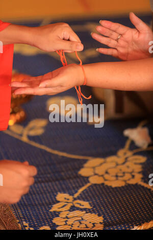 Liens moine coton bracetet béni (SAI-nas) autour d'un bracelet symbolisant le lien sacré. Cérémonie bouddhiste. Vat Simuong. Wat Si Muang. Vientiane. Le Laos. Banque D'Images