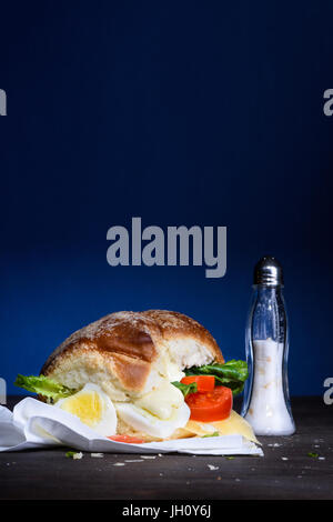 Oeufs savoureux Gourmet Burger avec des tomates, de la mayonnaise et de la salade sur une table en bois. Copier l'espace. Banque D'Images