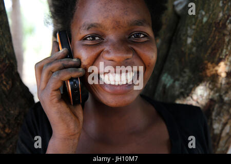 Smiling young girl en utilisant un téléphone cellulaire. L'Ouganda. Banque D'Images