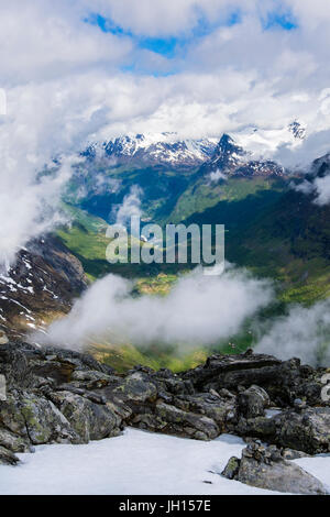 Vue vers le bas à travers les nuages de Geirangerfjorden avec montagnes aux sommets enneigés de la montagne Dalsnibba en été. Sunnmore, Geiranger, Norvège région Banque D'Images