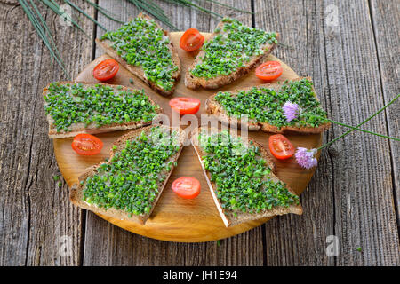 Jardin de bière nourriture : tranches de pain de campagne frais avec du beurre et de la ciboulette sur une planche en bois Banque D'Images