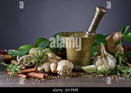 Ancien mortier en cuivre avec des épices et herbes sur table de cuisine. Banque D'Images