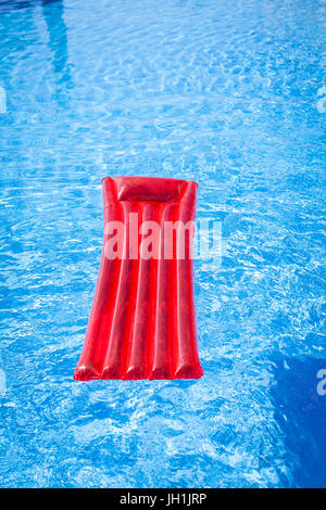 Chaise longue gonflable rouge lilo floating in a swimming pool Banque D'Images