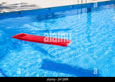 Chaise longue gonflable rouge lilo floating in a swimming pool Banque D'Images