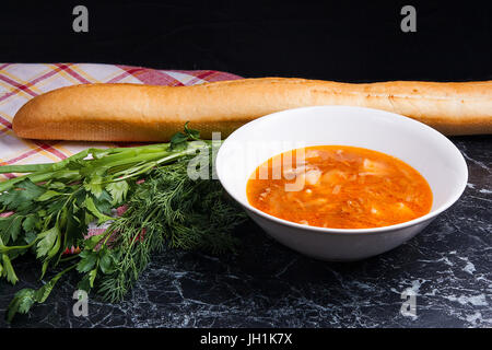 Les légumes et la viande dans la soupe borsch ou betteraves rouges en plaque blanche. Le pain blanc, les herbes - aneth, oignon vert, le persil autour de la plaque. Tomate ukrainien Banque D'Images