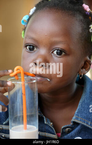 Jeune fille africaine de boire un verre de lait. Togoville. Le Togo. Banque D'Images