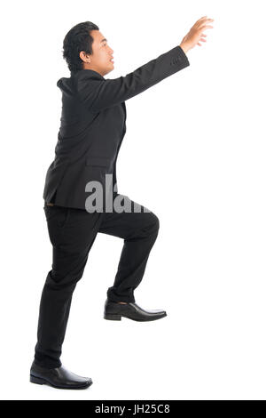 Corps plein side view of young businessman stepping up de l'Asie du Sud-Est et d'escalier, l'accaparement de la main quelque chose, isolé sur fond blanc. Banque D'Images