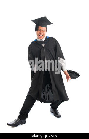 Corps plein excité Asian male university student in graduation gown jumping high, isolé sur fond blanc. Banque D'Images