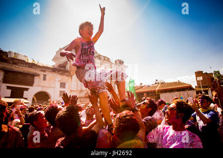 Garçon d'être jetée en l'air pendant le festival Holi Jeter Pigment dans Durbar Square, Katmandou, Népal, Asie Banque D'Images