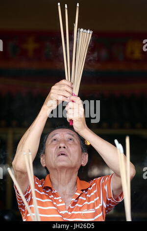 Lian Shan Shuang Lin, monastère. Un Chinois priant et offrant de l'encens. Adorateur bouddhiste. La combustion d'encens. Singapour. Banque D'Images